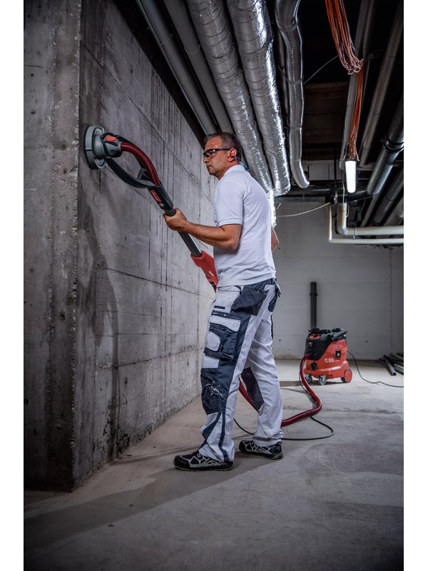 Girafe béton FLEX GDE 10 en ponçage d’un mur en béton, tuyau d’aspiration raccordé à l’aspirateur